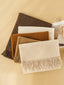 Set of four woven scarfs in brown, beige, and cream with fringes on a beige background.