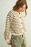 Woman wearing a striped sweater with buttons on a plain background