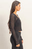 Woman wearing a black lace top and leggings against a beige background