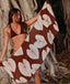 Woman holding a brown towel with white leaf patterns against a natural background