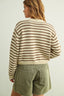 Woman wearing a striped sweater and green shorts against a plain background