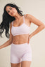 Woman wearing a light pink checkered sports bra and shorts set on a beige background