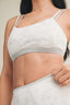 White sports bra with gray trim worn by a person against a neutral background