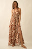 Woman wearing a long, patterned dress with a slit on a beige background