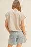 Person wearing a beige top and denim shorts on a plain background