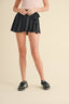 Person wearing a black skirt with a bow detail on a beige background