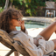 Woman relaxing on a lounge chair by a poolside