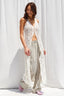 Woman wearing a white lace cover-up over a striped swimsuit against a white curtain background
