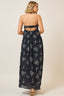 Woman wearing a navy floral dress with cut-out back on a beige background