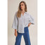 Woman wearing a striped shirt and blue jeans against a beige background