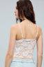 Woman wearing a lace crop top with thin straps on a gray background