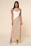 Woman wearing a two-tone dress with a white top and beige skirt on a beige background