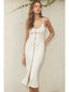Woman wearing a white dress with buttons against a neutral background