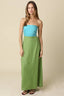 Woman wearing a strapless turquoise top and green skirt against a beige background