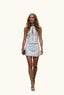 A woman wearing a white sleeveless mini dress with a front zipper and keyhole cutout, paired with white heeled sandals.