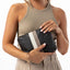 Woman holding a black clutch with a white stripe on a white background