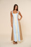 Woman wearing a long, light blue and beige dress against a beige background